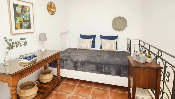 A bedroom with a bed, bedside tables, a desk, a lamp, and a clock.