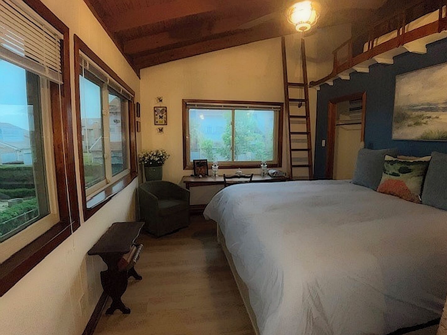 Una camera da letto con un letto, una scrivania, una sedia, una finestra e un quadro appeso al muro.