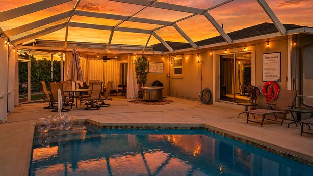 Zona de piscina exterior techada con patio, asientos y mesa de billar.