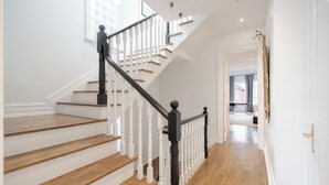 A staircase with white balusters and black handrails, leading to a second-floor landing. - Rare Yorkville Detached House with Parking and Hot Tub (Toronto)