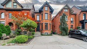 A residential street with brick houses, a paved driveway, and a parked car. - Rare Yorkville Detached House with Parking and Hot Tub (Toronto)