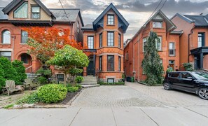Une rue résidentielle bordée de maisons en briques, avec une allée pavée et une voiture garée.