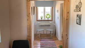 Ein Flur mit Holztürrahmen, einem Heizkörper, einem Fenster mit Pflanze und einem Tisch mit Stühlen.