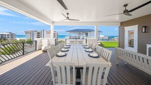 A covered outdoor dining area with a view of the ocean, white furniture, and a ceiling fan. - Direct Beach Access, Panoramic Rooftop, Pool/Spa (Clearwater)