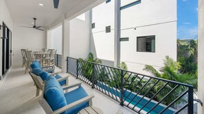 A balcony with outdoor seating, a pool, and a white building with windows. - Direct Beach Access, Panoramic Rooftop, Pool/Spa (Clearwater)