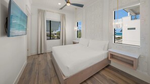 A bedroom with a bed, a ceiling fan, a window with a view, and a nightstand. - Direct Beach Access, Panoramic Rooftop, Pool/Spa (Clearwater)