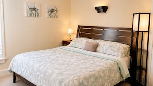 A bedroom with a bed, a nightstand, a lamp, and wall art.