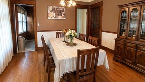 A dining room with a wooden table, chairs, a chandelier, and a cabinet.