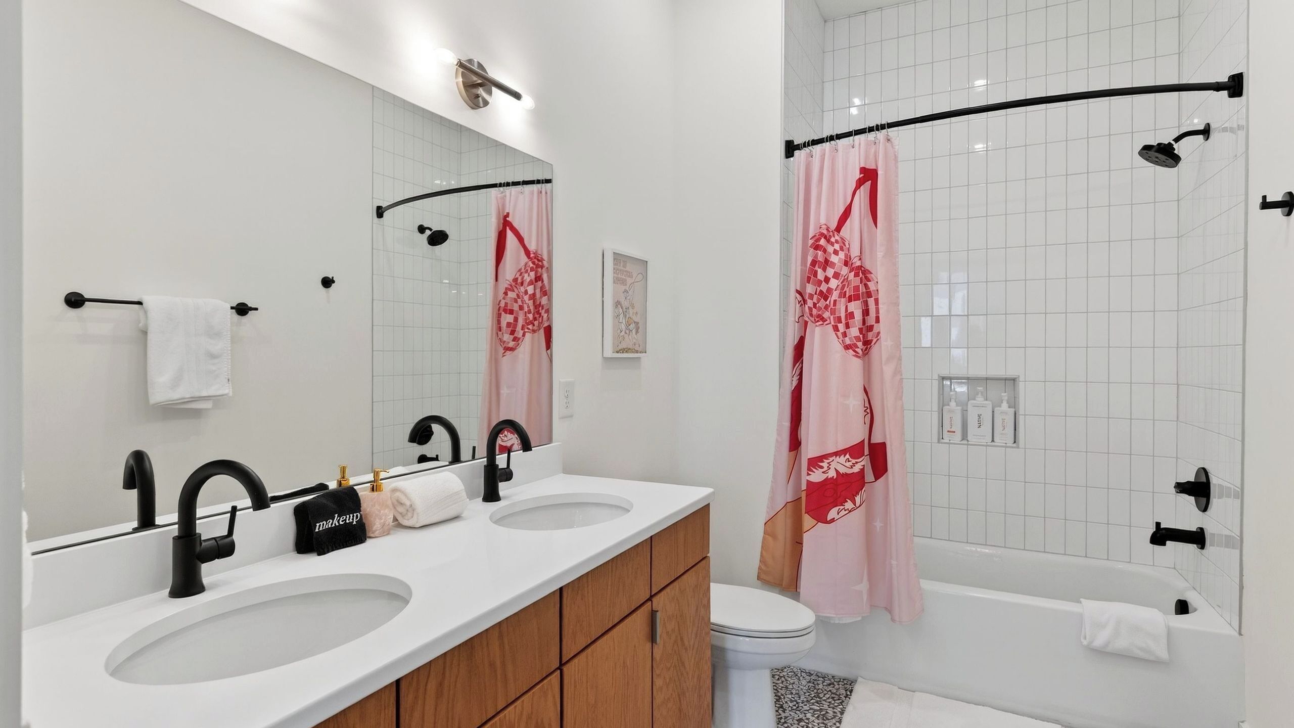 A modern bathroom with two sinks, a shower, and a toilet.