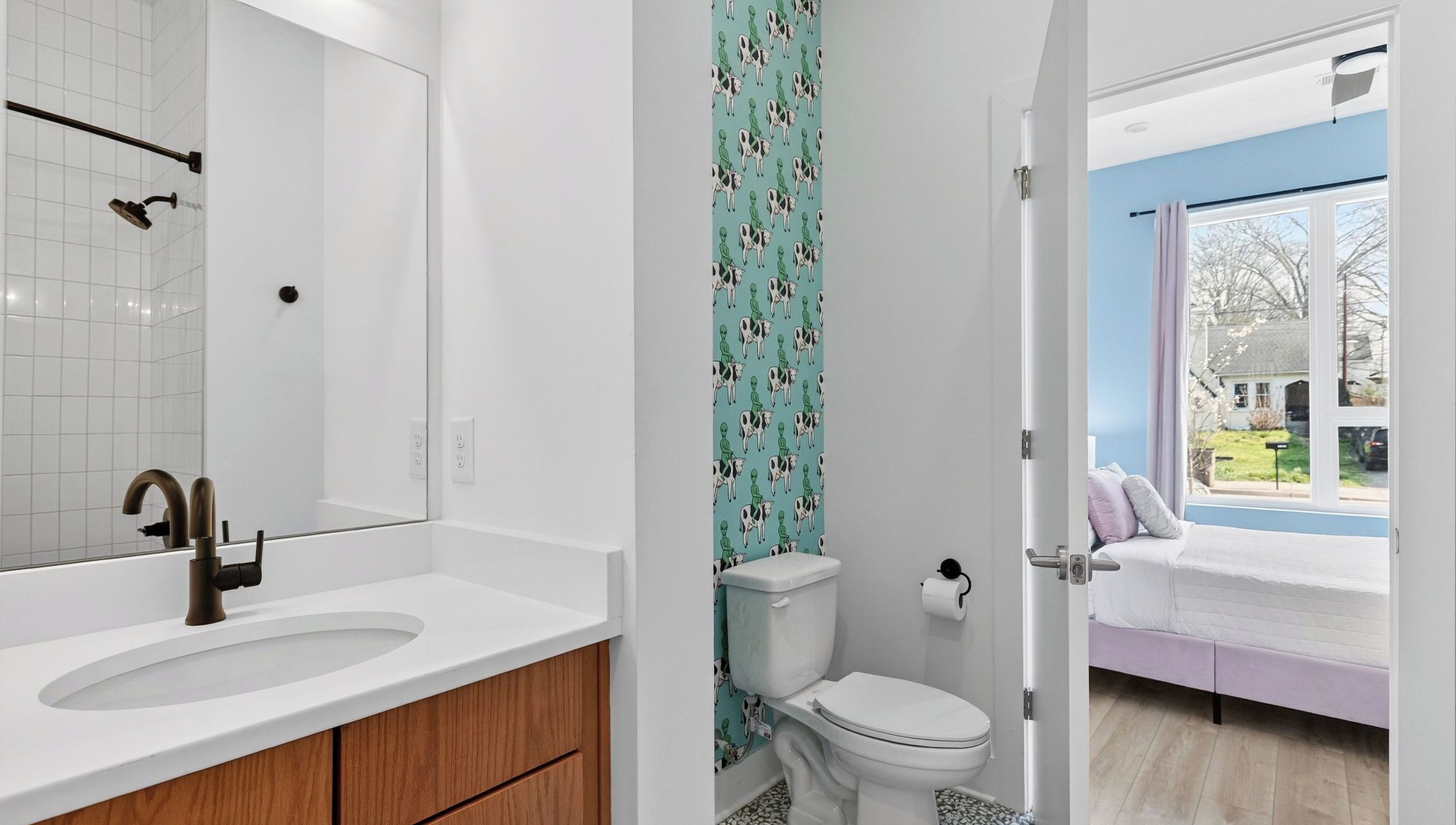 A bathroom with a white sink, a mirror, a toilet, and a shower.