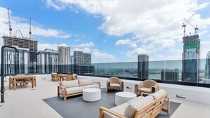 A rooftop lounge with outdoor furniture, a glass balustrade, and a city skyline view. - Modern Downtown Suite with Full Amenity Access (Miami)
