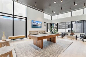 A modern indoor space with a pool table, seating area, and large windows offering views of the city. - Modern Downtown Suite | Walk to Bayfront Park (Miami)