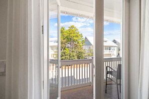 A view from a balcony with a railing, a chair, and a clear sky with clouds.