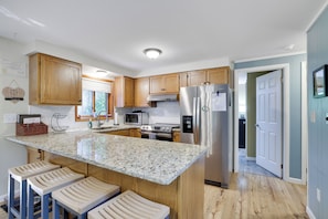 A kitchen with wooden cabinets, a stainless steel refrigerator, a granite countertop, and a built-in island with bar stools. - Cozy 4-bedroom chalet in The Hideout pet friendly with AC, hot tub (Cobbs Lake Preserve)