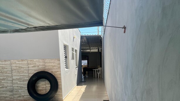 A poolside area with a tiled floor, a black tire, and a covered patio.
