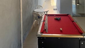A narrow corridor with a pool table, chairs, and a small table.