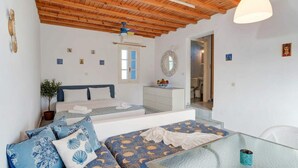 A bedroom with a bed, a sofa, a dresser, a mirror, and a ceiling fan. - Ornos Home With Sea View (Mykonos)