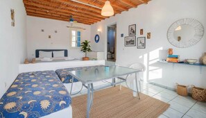 Ein modernes Zimmer mit einem Glastisch, einer blauen gepolsterten Couch, einer Holzbalkendecke und einer Wand mit gerahmten Bildern.