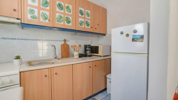 A kitchen with wooden cabinets, a sink, a microwave, a coffee maker, and a refrigerator. - Ornos Home With Sea View (Mykonos)