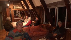 A cozy indoor setting with wooden beams, a dining table, and a sofa. - Hostal La Minga (Chaiten)