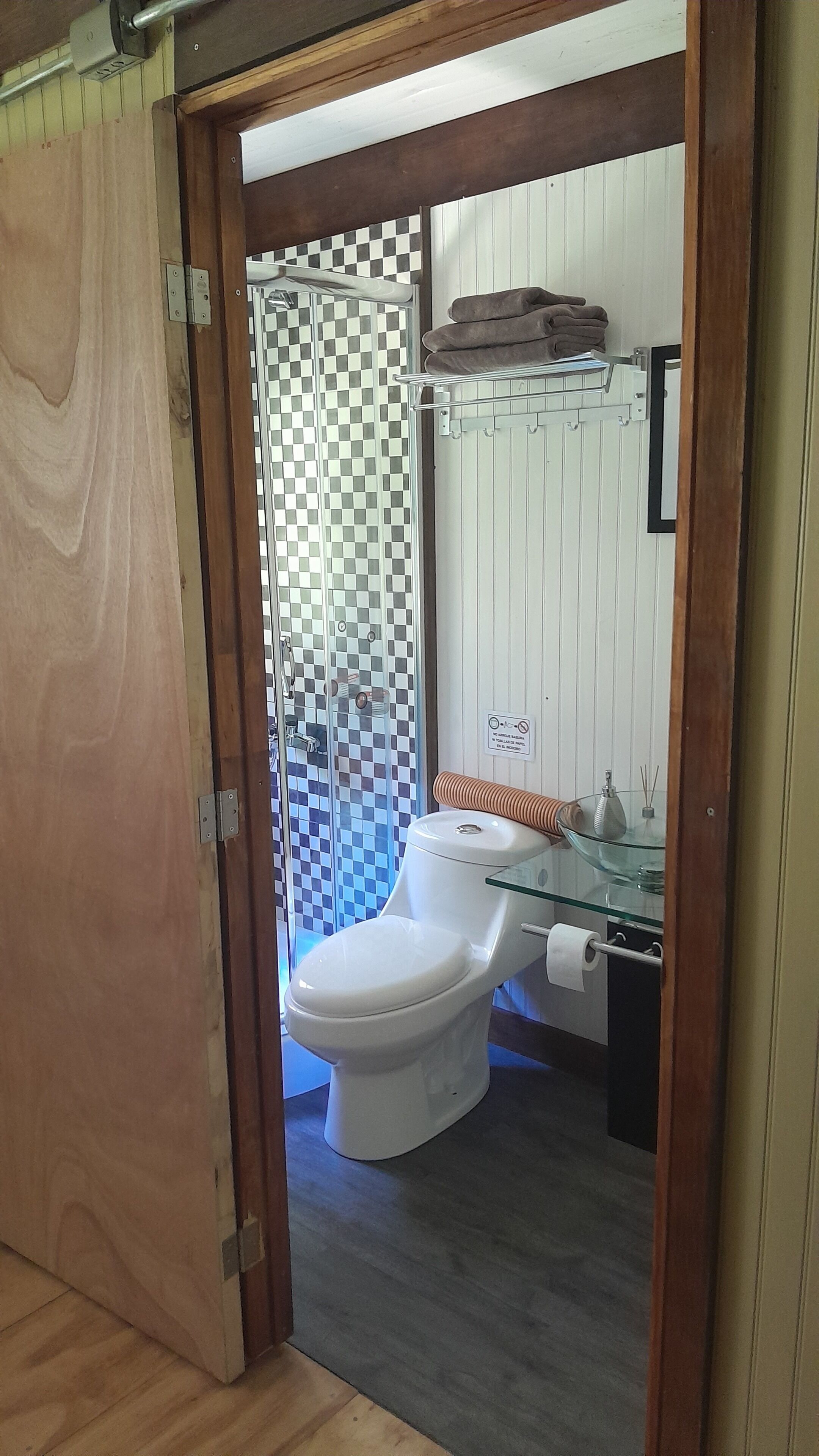 Une salle de bain équipée de toilettes, d’une douche à parois de verre et d’un porte-serviettes.