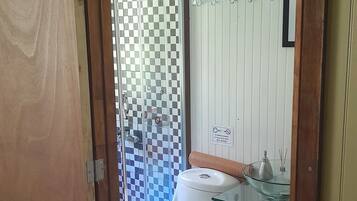 Une salle de bain équipée de toilettes, d’une douche à parois de verre et d’un porte-serviettes.