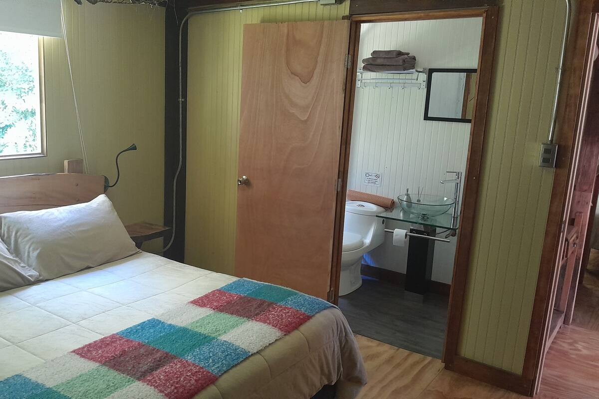 Ein Schlafzimmer mit Bett, einer Tür zu einem Badezimmer und einem Fenster.