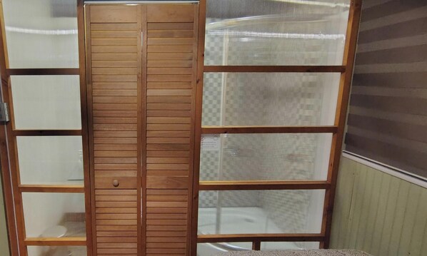 Ein Zimmer mit einem Holzschrank, einem Bett und einem Fenster mit Jalousien.