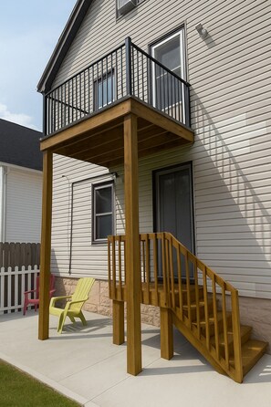 A two-story house with a wooden deck and a staircase leading to a balcony. - ALL INCLUSIVE Clean, Safe, and Furnished for those seeking a home away from home (Buffalo)