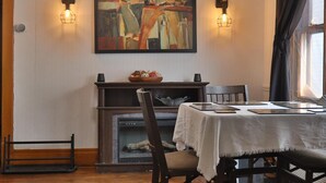 Un coin repas comprenant une table, des chaises, un ventilateur de plafond, une cheminée et un tableau au mur.