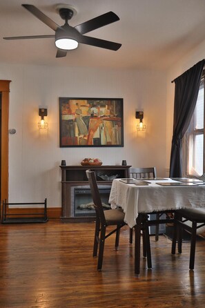 A dining area with a table, chairs, a ceiling fan, a fireplace, and a painting on the wall. - ALL INCLUSIVE Clean, Safe, and Furnished for those seeking a home away from home (Buffalo)