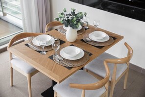 Une table à manger dressée avec des assiettes, des verres et un vase rempli de verdure.
