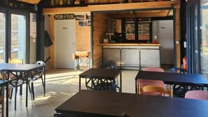 A rustic interior with wooden beams, a bar area, and tables and chairs. - LE FAUCON PELERIN - TOURNAVAUX (TOURNAVAUX)