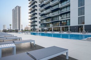 Ein modernes Gebäude mit Pool auf dem Dach, Liegestühlen und Außenbereich.