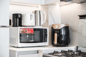 Eine Küche mit einer GEERPS-Mikrowelle, einer Kaffeemaschine und einer schwarzen Espressomaschine.