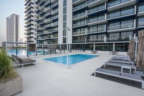 Ein modernes Gebäude mit Pool auf dem Dach, Außenbereich zum Sitzen und freiem Blick auf die Umgebung.