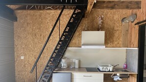 A compact kitchen with a built-in stove, a small refrigerator, a sink, and a trash bin.