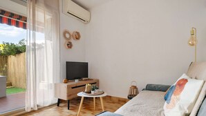 A modern bedroom with a TV, wooden furniture, a small round table, and a bed with decorative pillows. - Carry Le Rouet, Proche Plages, Commerces (Carry-le-Rouet)