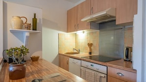 A kitchen with wooden cabinets, a stainless steel refrigerator, a dishwasher, and a countertop with a plant and utensils. - Carry Le Rouet, Proche Plages, Commerces (Carry-le-Rouet)