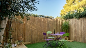 A small outdoor patio with a table and chairs, surrounded by a bamboo fence and green artificial grass. - Carry Le Rouet, Proche Plages, Commerces (Carry-le-Rouet)