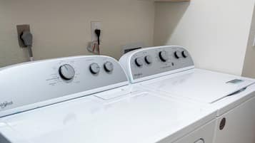 A front view of a Whirlpool washer and dryer unit in a kitchen with wooden cabinets above.