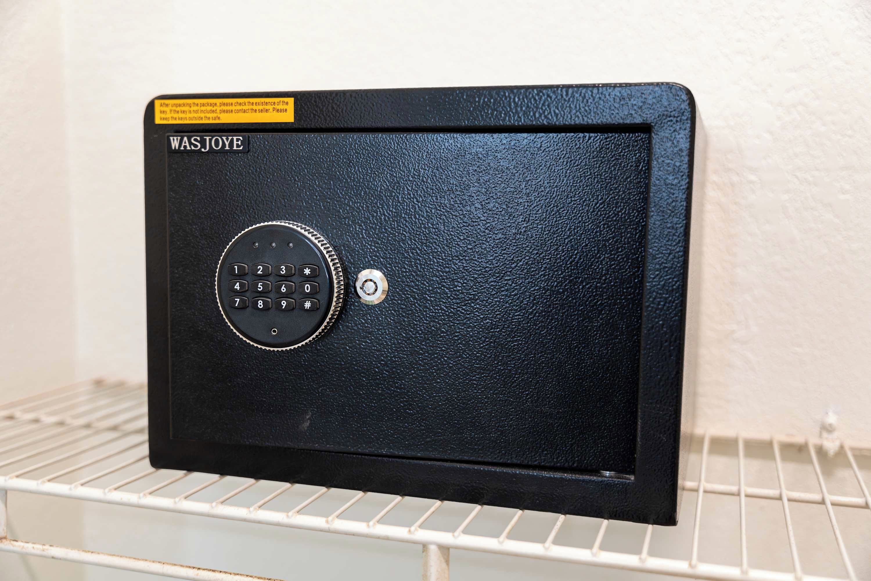 A black safe with a keypad on a white shelf.