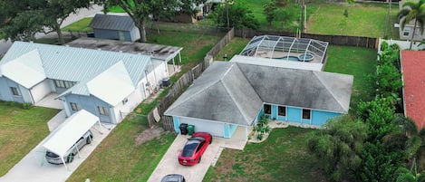 Un quartier résidentiel avec des maisons, une piscine et une voiture rouge garée dans l’allée.
