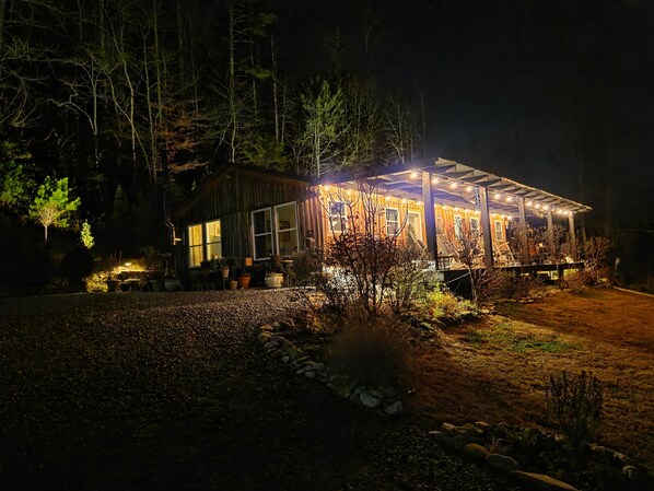 A wooden cabin with a covered porch, surrounded by trees and potted plants. - 52 acre Cabin "The Outdoor Inn" w Hot Tub & Creek (Lenoir)