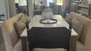 A dining area with a table, chairs, a hanging light fixture, and a view of the outdoors. - The Outdoor Inn (Lenoir)