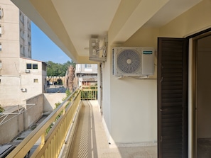 Ein Balkon mit Blick auf ein Gebäude, eine Klimaanlage und eine Tür.