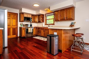 A kitchen with wooden cabinets, a stainless steel refrigerator, a microwave, and a sink.