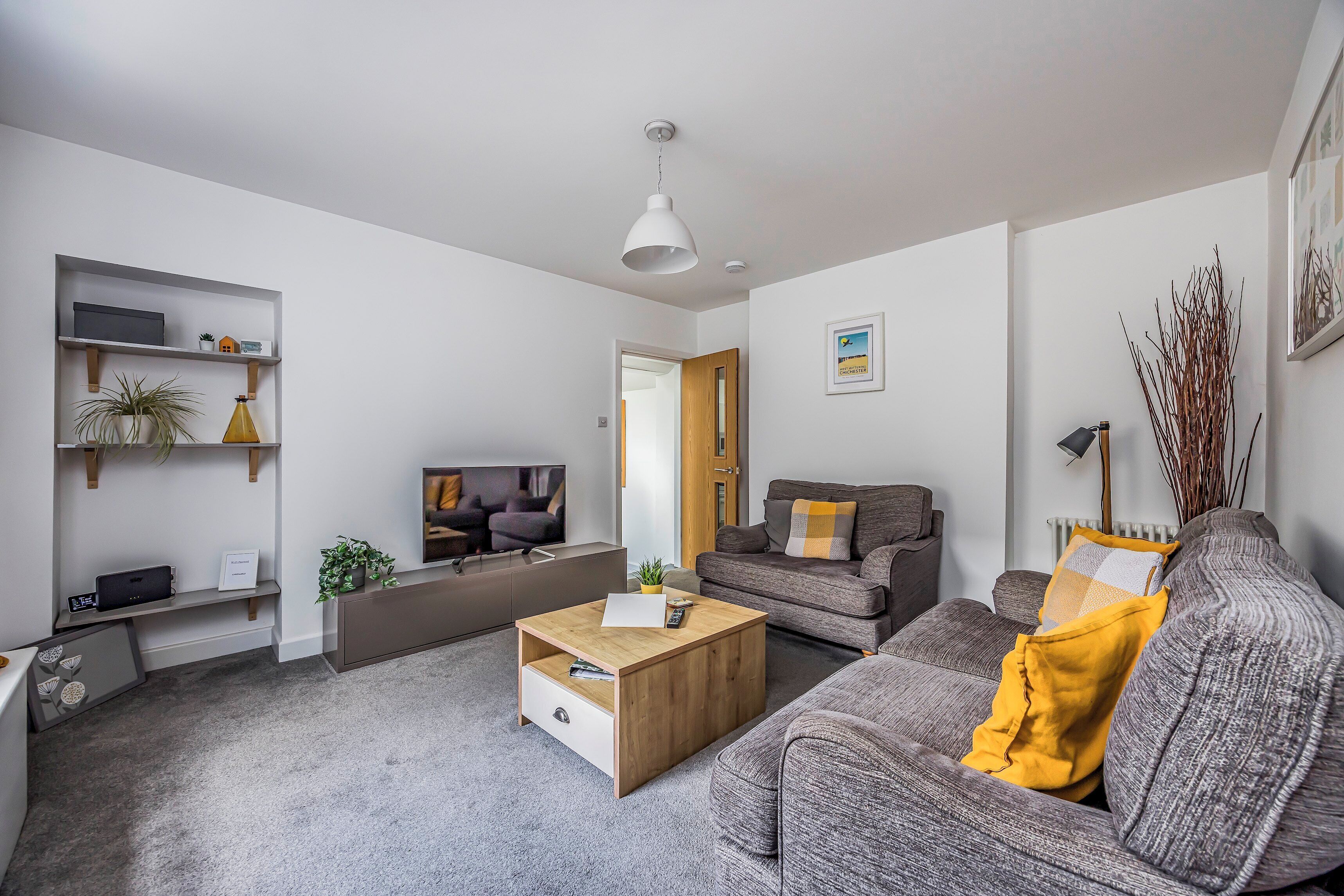 A modern living room with a sofa, coffee table, TV, and shelves.