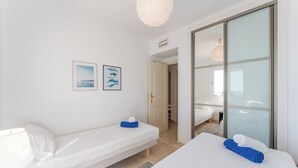 Ein Hotelzimmer mit einem Bett, einem kleinen Nachttisch, einer Lampe, einem Wandbild und einer Schiebetür zu einem anderen Raum.