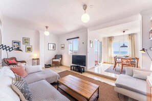A modern living room with a sofa, a coffee table, a TV, and a dining area with a table and chairs. - 3 Bed with Panoramic Sea views - Pass the Keys (Fuengirola)